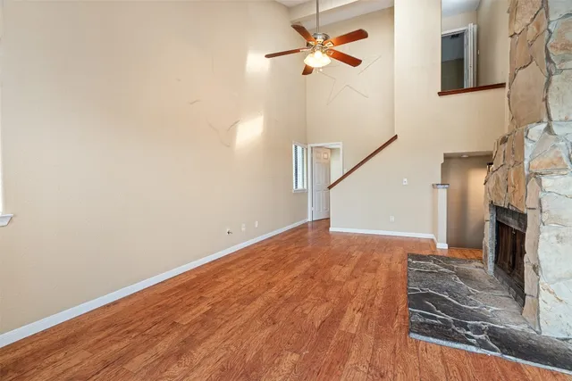 a view of a livingroom with wooden floor a ceiling fan and staircase