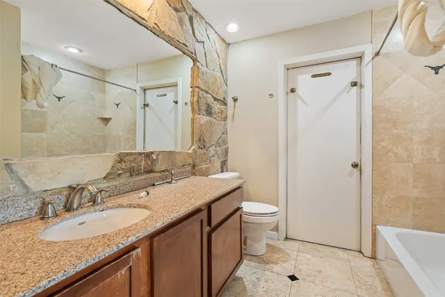 a bathroom with a granite countertop sink a toilet a mirror and shower