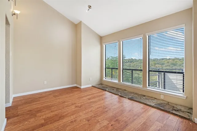 a view of an empty room with a window and wooden floor