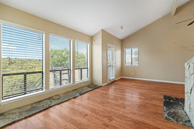 a view of an empty room with a window and wooden floor