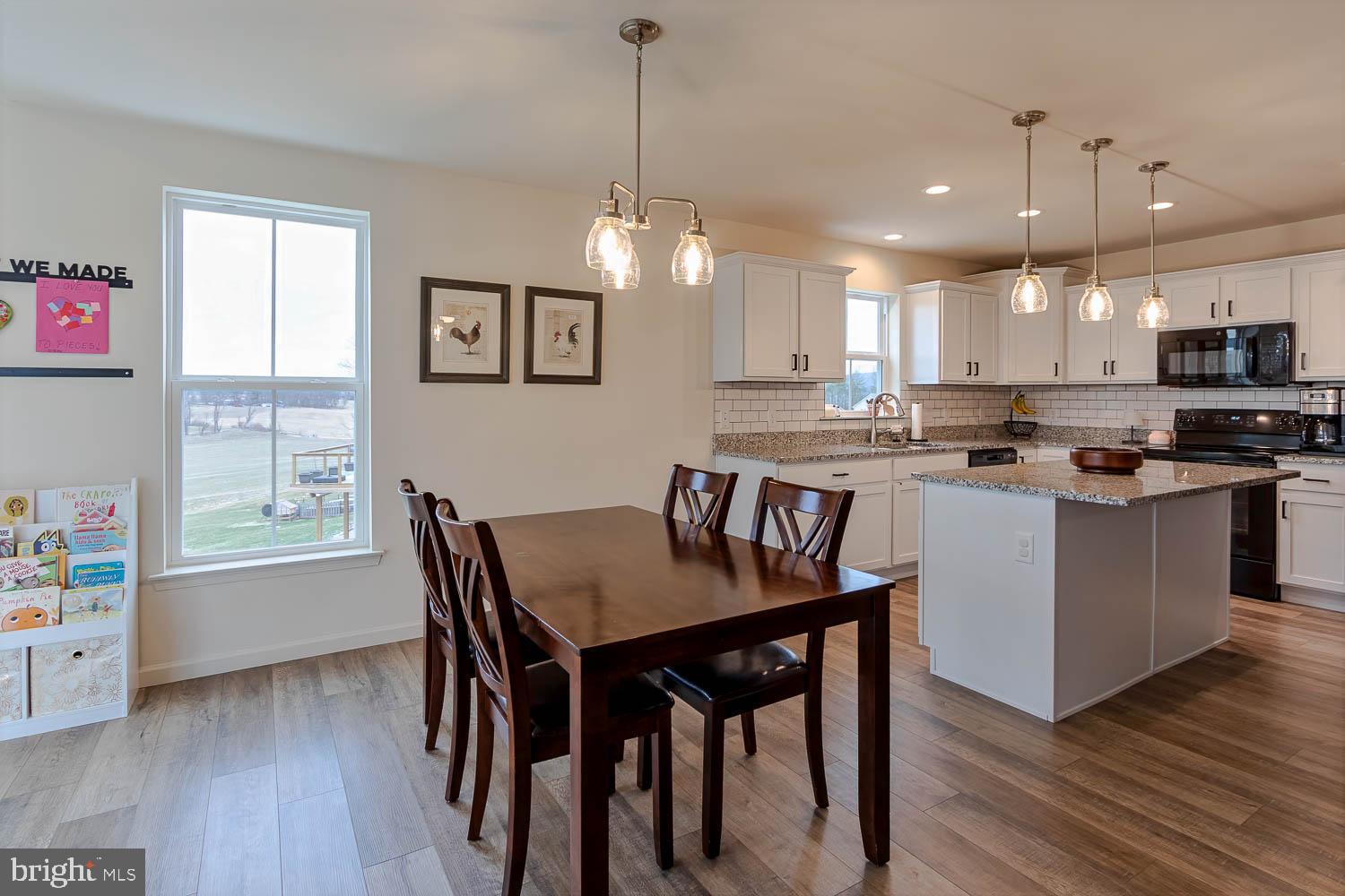 204 Whitetail Circle Mill Hall, PA 17751 - Photo 11 of 33 a kitchen with stainless steel appliances granite countertop a stove a refrigerator a kitchen island a dining table and chairs with wooden floor