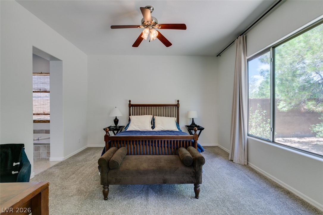 8 Kennesaw Road Henderson, NV 89052 - Photo 29 of 44 A well-lit primary bedroom offers serene views of the outdoors and a connection to a private en suite.