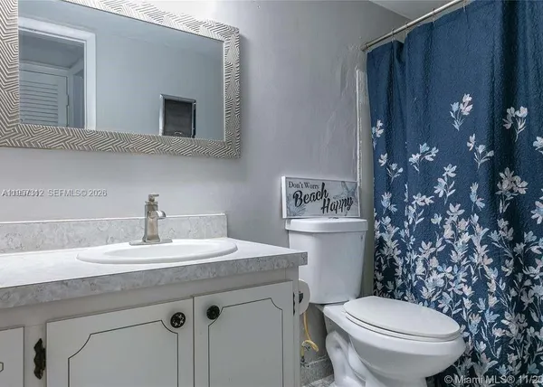 a bathroom with a granite countertop toilet sink and mirror