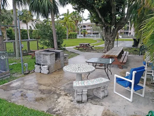 a view of a patio with table and chairs potted plants and a large tree