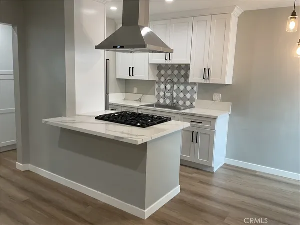 a kitchen with a stove and a wooden floor