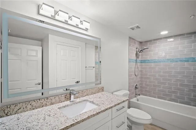 a bathroom with a granite countertop sink a toilet and shower