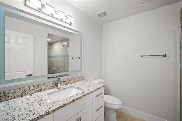 a bathroom with a granite countertop sink a toilet and a mirror