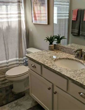 a bathroom with a granite countertop sink toilet and mirror