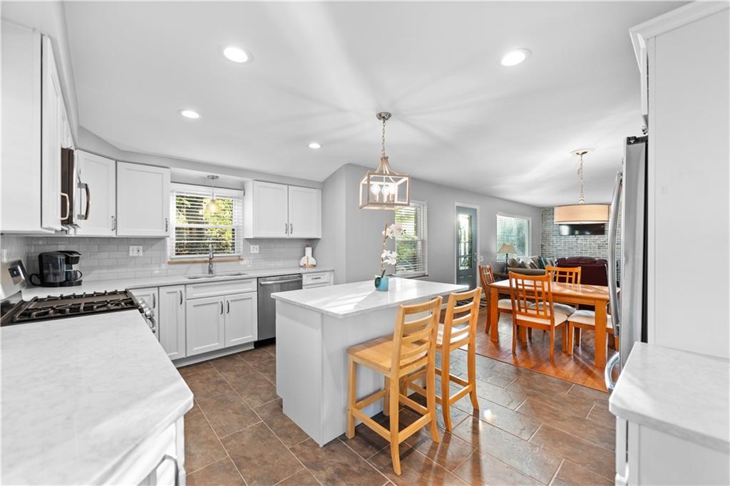 3318 Ivanhoe Road Pittsburgh, PA 15241 - Photo 8 of 45 a kitchen with stainless steel appliances kitchen island granite countertop a stove top oven a sink a dining table and chairs with wooden floor