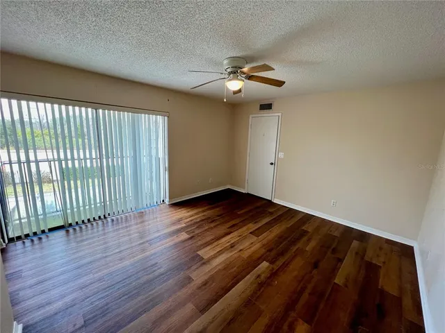 a view of a room with a ceiling fan and hardwood floor