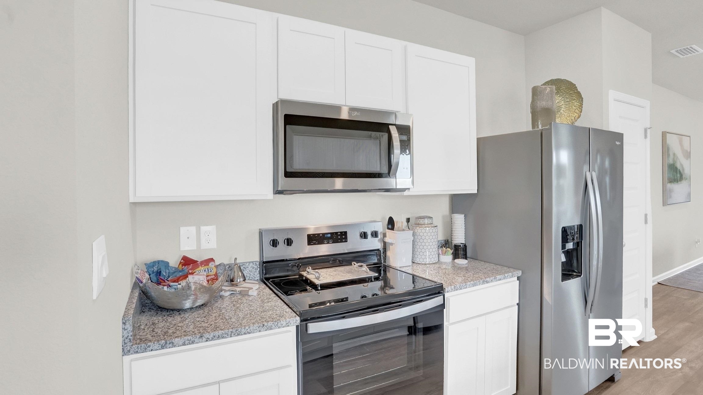 13330 Shea Circle Foley, AL 36535 - Photo 7 of 15 Kitchen featuring white cabinetry, granite-style countertops, and stainless steel appliances including a refrigerator, range, and microwave