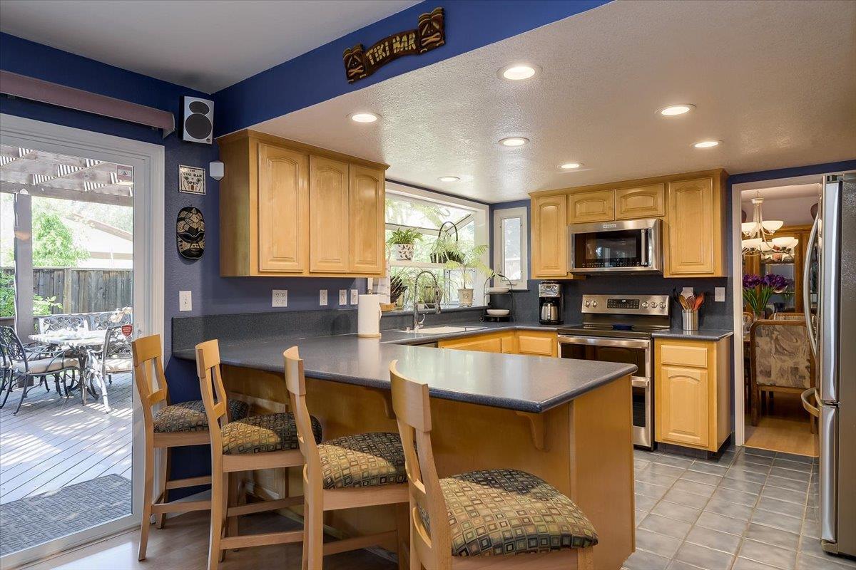 1635 Serpa Drive Milpitas, CA 95035 - Photo 13 of 31 a kitchen with stainless steel appliances granite countertop dining table chairs sink and wooden cabinets