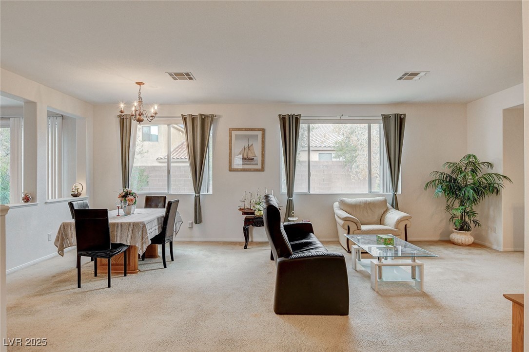 7427 Wagonwheel Ranch Way Las Vegas, NV 89113 - Photo 11 of 50 Dining room featuring a chandelier, plenty of natural light, and light carpet