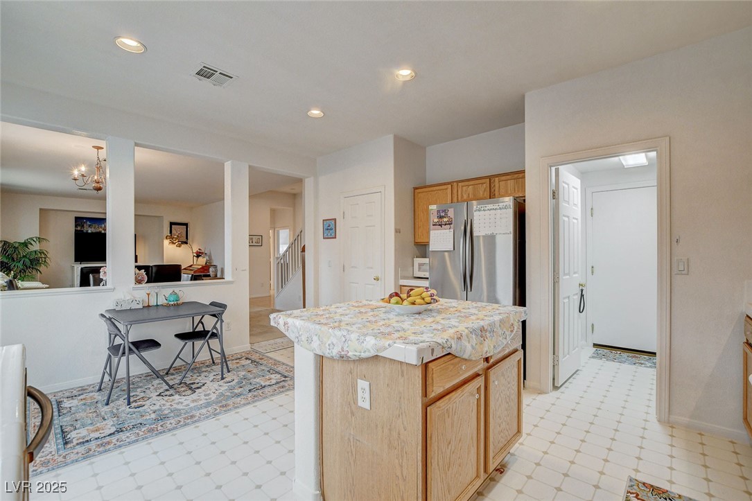 7427 Wagonwheel Ranch Way Las Vegas, NV 89113 - Photo 14 of 50 Kitchen featuring freestanding refrigerator, light flooring, light countertops, a kitchen island, and a chandelier