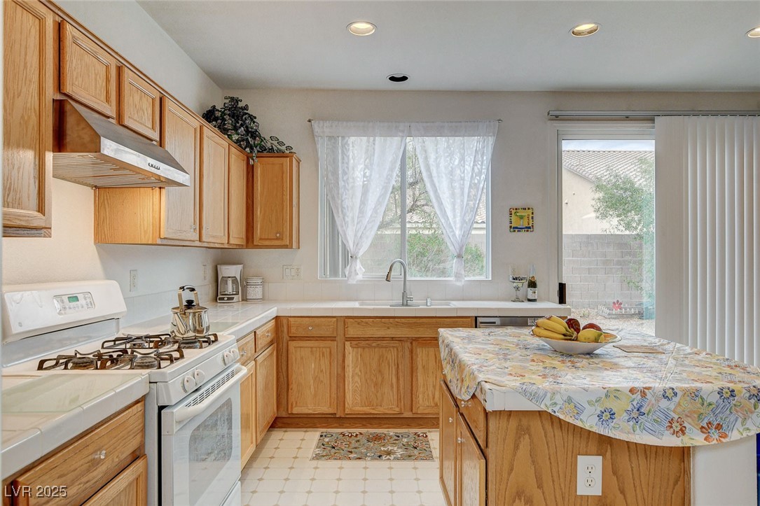 7427 Wagonwheel Ranch Way Las Vegas, NV 89113 - Photo 16 of 50 Kitchen featuring white gas stove, under cabinet range hood, tile countertops, recessed lighting, and light flooring