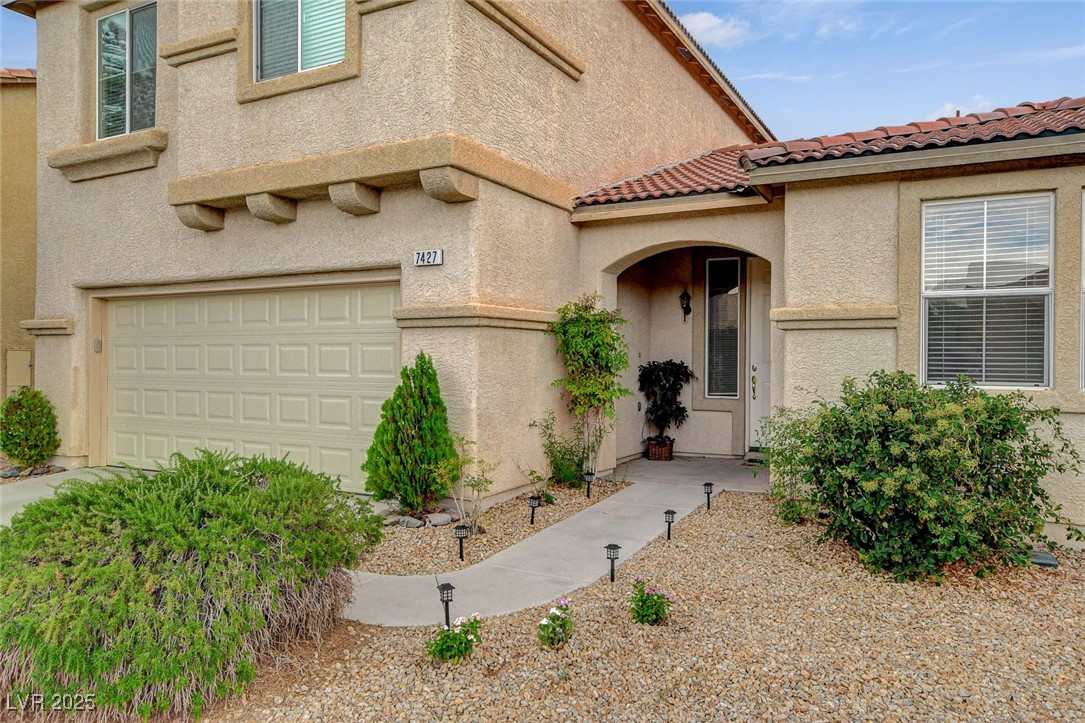 7427 Wagonwheel Ranch Way Las Vegas, NV 89113 - Photo 4 of 50 Entrance to property featuring a garage, stucco siding, and a tiled roof