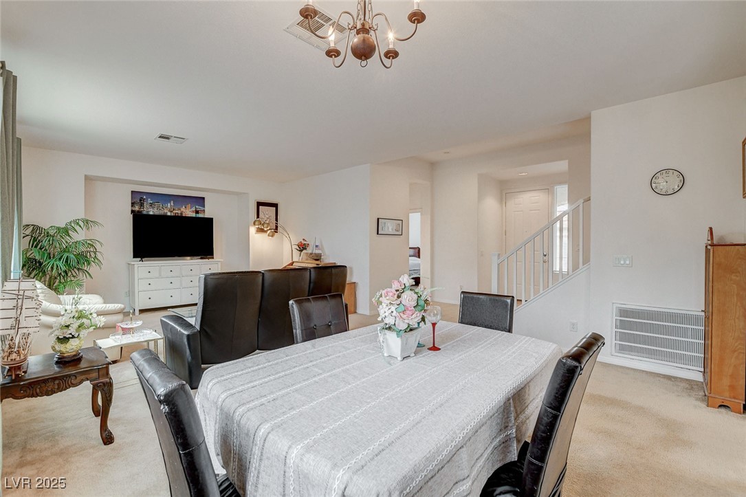 7427 Wagonwheel Ranch Way Las Vegas, NV 89113 - Photo 10 of 50 Dining room with light colored carpet, stairway, and a chandelier