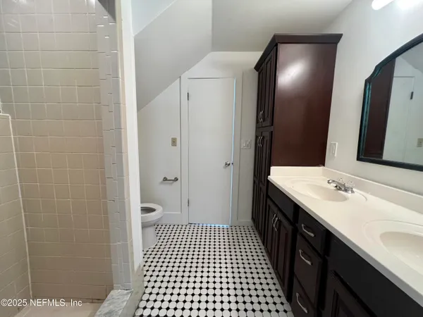 a bathroom with a double vanity sink a toilet and a mirror