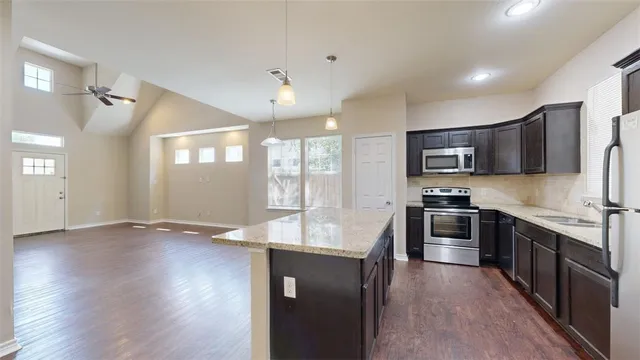 a large kitchen with stainless steel appliances granite countertop a stove and a wooden floors