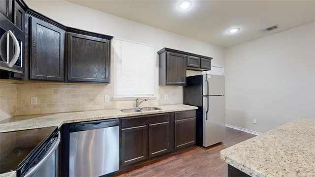 a kitchen with stainless steel appliances granite countertop a sink stove and refrigerator