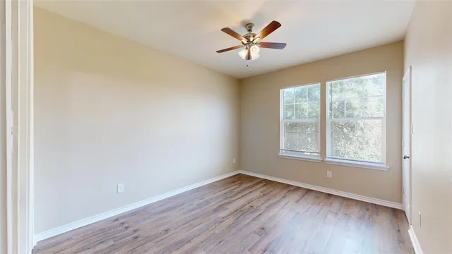 a view of a hallway with wooden floor and a bathroom