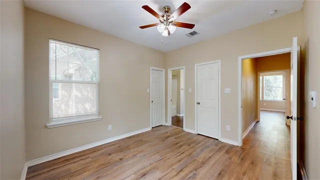 an empty room with wooden floor and windows