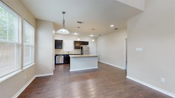 a view of kitchen with kitchen island granite countertop a stove oven and white cabinets with wooden floor