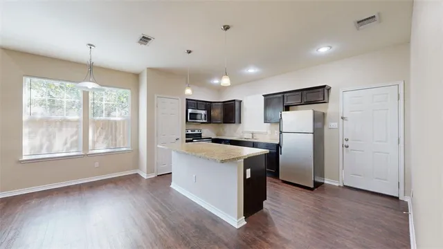 a kitchen with refrigerator a stove and wooden floor