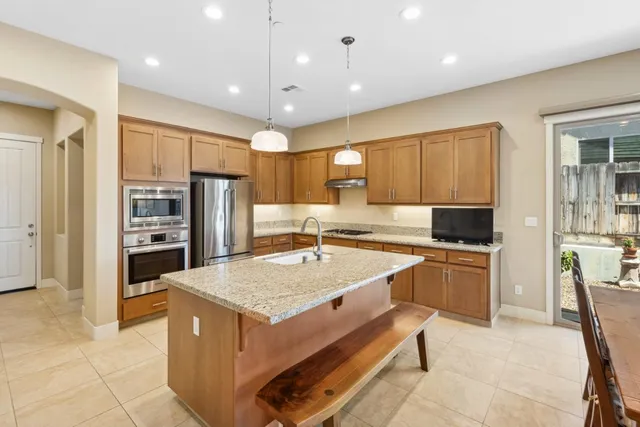a kitchen with stainless steel appliances granite countertop a refrigerator a sink and a stove
