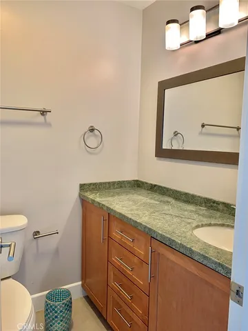 a bathroom with a granite countertop toilet sink and mirror