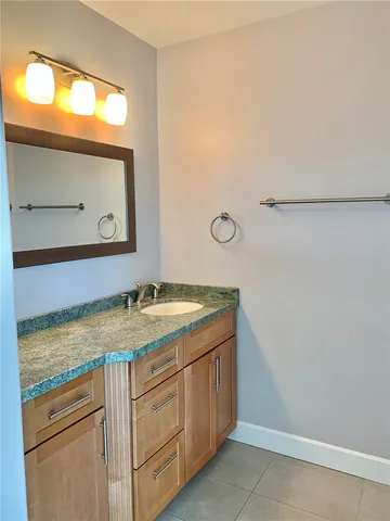 a bathroom with a granite countertop sink and a mirror