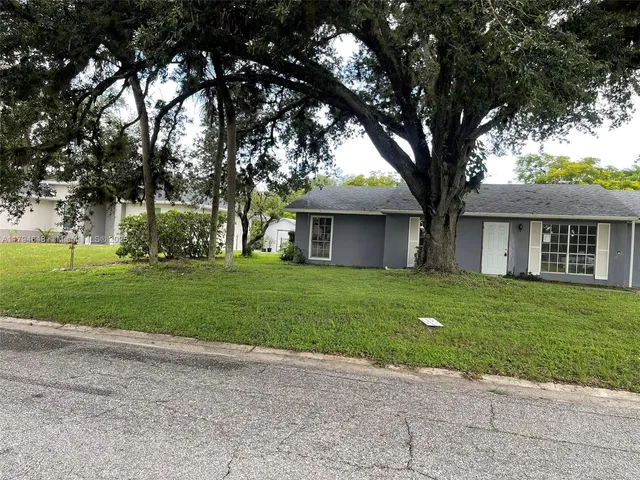 a front view of a house with a garden and trees