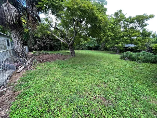 a backyard of a house with lawn chairs plants and tree