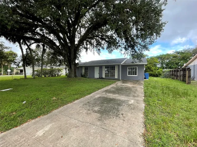 a view of house with a big yard potted plants and large tree