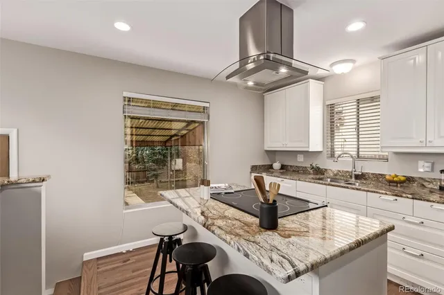 a kitchen with granite countertop a stove a sink and a refrigerator