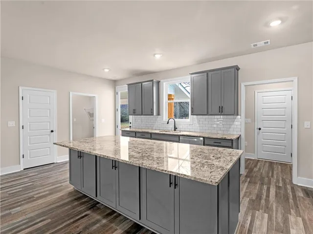 a large kitchen with granite countertop a sink and cabinets