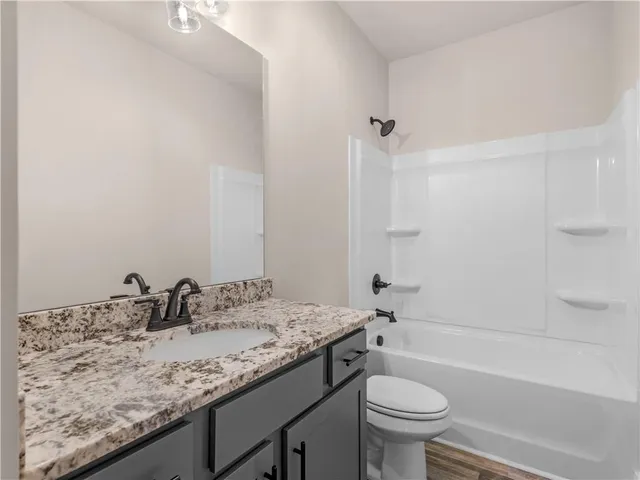 a bathroom with a granite countertop sink a toilet and a bathtub