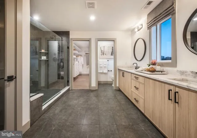 a spacious bathroom with a double vanity sink a large mirror and shower