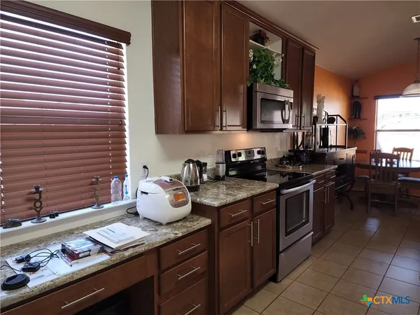 a kitchen with granite countertop cabinets a stove and a window
