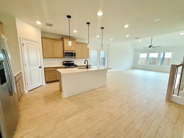 a large kitchen with stainless steel appliances kitchen island granite countertop a stove a sink and a refrigerator