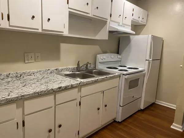 a kitchen with granite countertop white cabinets and white appliances