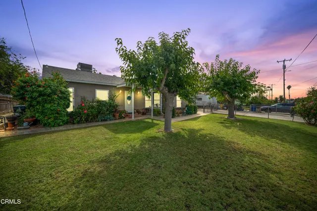 a view of a house with a big yard and palm trees