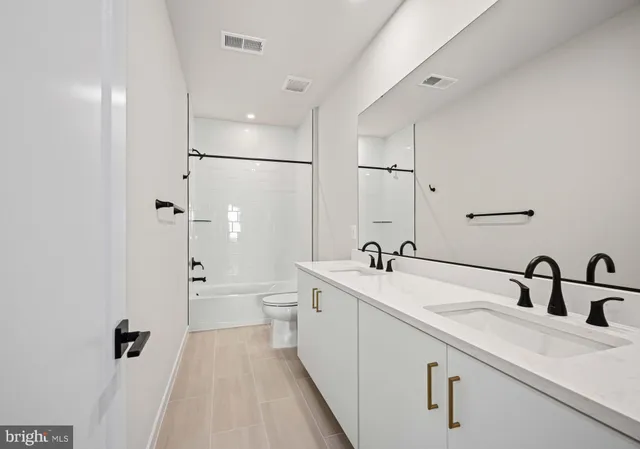 a spacious bathroom with a double vanity sink a mirror and a shower
