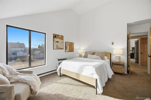 a bedroom with a bed couch and large window