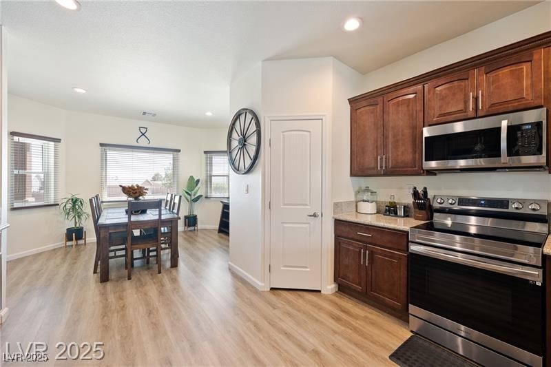760 Fort Churchill Road Pahrump, NV 89060 - Photo 5 of 33 Kitchen featuring appliances with stainless steel finishes, light stone countertops, dark brown cabinets, recessed lighting, and light wood finished floors