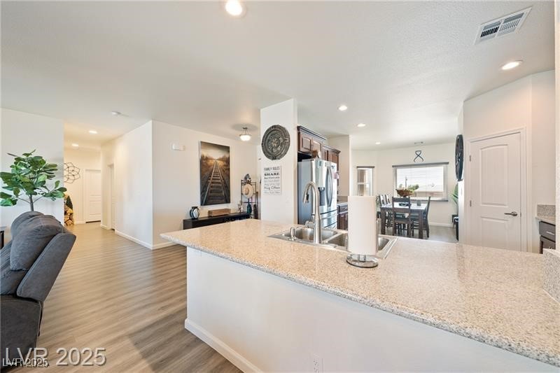760 Fort Churchill Road Pahrump, NV 89060 - Photo 33 of 33 Kitchen with open floor plan, a peninsula, light wood-style flooring, stainless steel fridge with ice dispenser, and light stone countertops