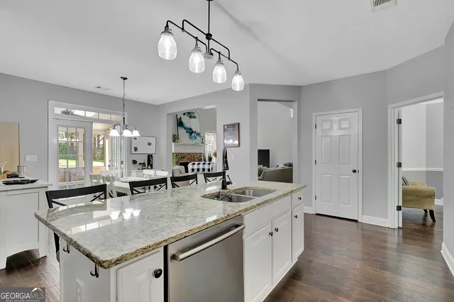 a kitchen with stainless steel appliances granite countertop a sink dishwasher and cabinets with wooden floor