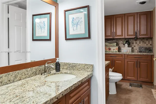 a bathroom with a granite countertop sink and a toilet