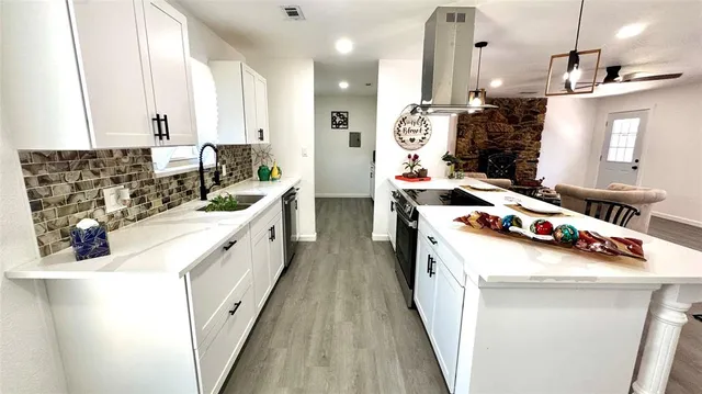 a kitchen that has a lot of white cabinets and stainless steel appliances