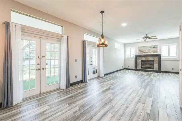 an empty room with windows fireplace and a ceiling fan